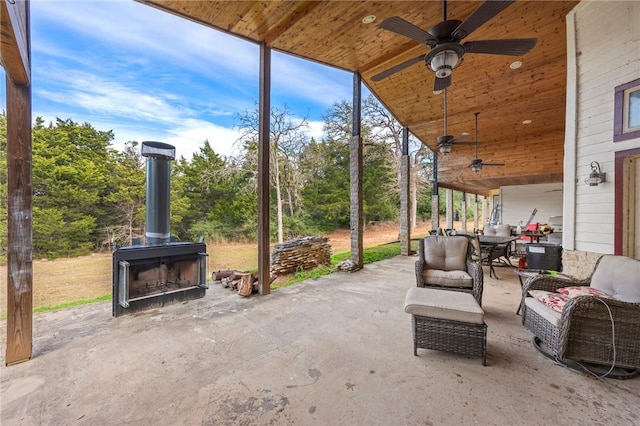 view of patio / terrace with ceiling fan and an outdoor living space with a fireplace