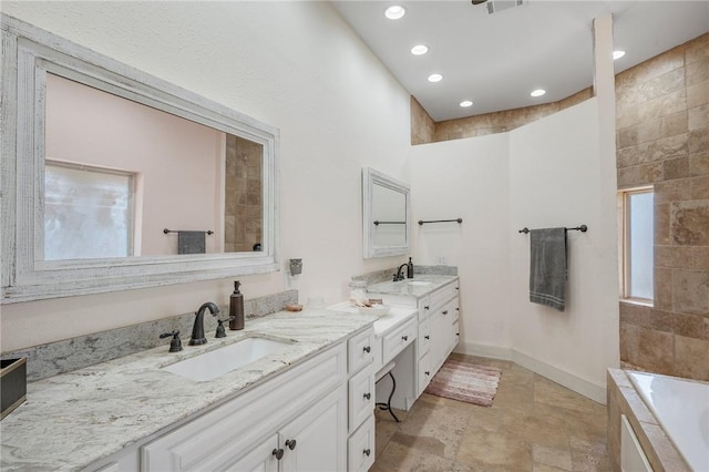 bathroom with tiled tub and vanity