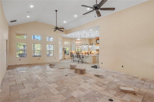 unfurnished living room featuring ceiling fan and a towering ceiling