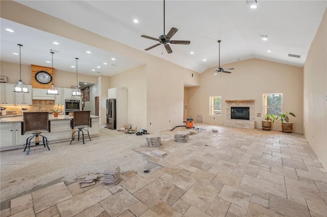 unfurnished living room with ceiling fan and high vaulted ceiling