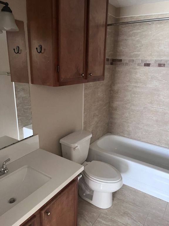 full bathroom featuring tiled shower / bath, tile patterned floors, vanity, and toilet