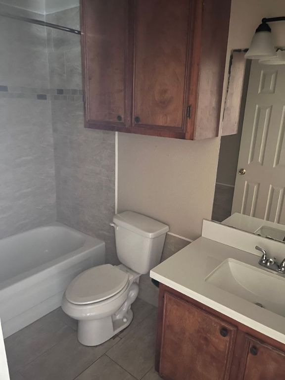 full bathroom featuring tile patterned floors, vanity, toilet, and tiled shower / bath combo