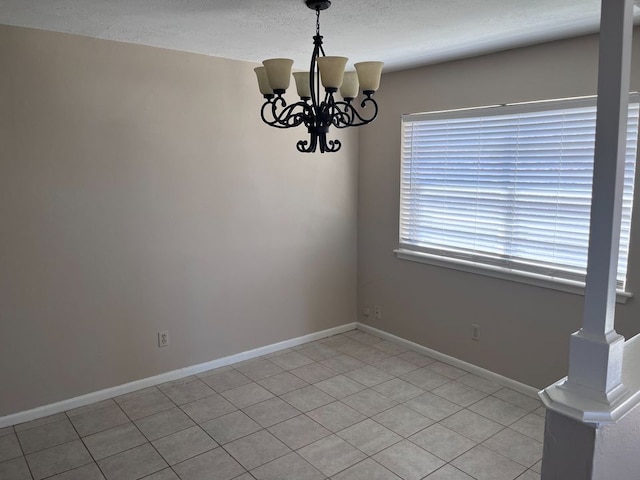 spare room with light tile patterned floors and an inviting chandelier