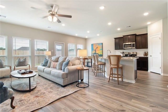 living room featuring light hardwood / wood-style floors, ceiling fan, and sink