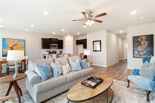 living room featuring ceiling fan and light hardwood / wood-style flooring