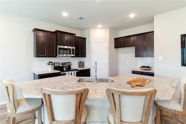 kitchen featuring a kitchen breakfast bar, tasteful backsplash, stainless steel appliances, sink, and a center island with sink