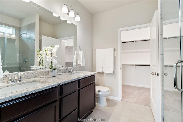 bathroom with tile patterned floors, vanity, a shower with shower door, and toilet