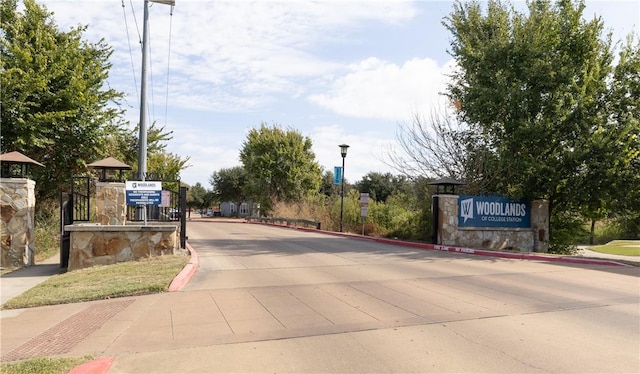 view of road with a gated entry, curbs, and street lights