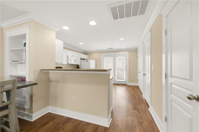 kitchen featuring visible vents, white appliances, dark wood-type flooring, and ornamental molding