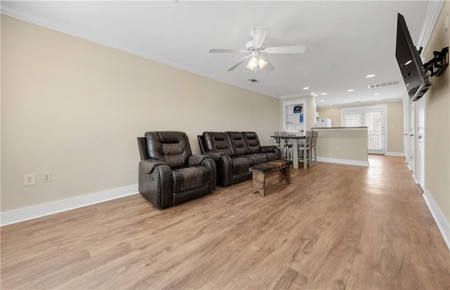 living area with visible vents, baseboards, crown molding, and light wood-style floors