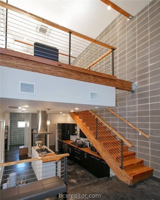 stairway with concrete flooring, tile walls, and a high ceiling