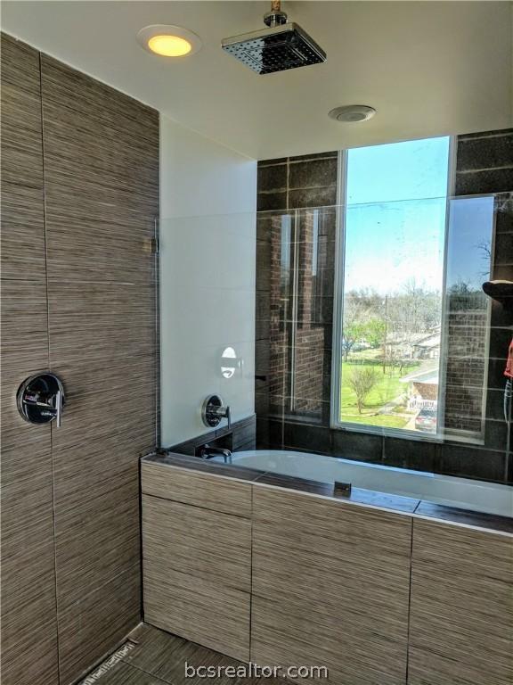 bathroom featuring plus walk in shower and tile walls