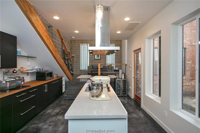 kitchen with island exhaust hood, a center island, and hanging light fixtures