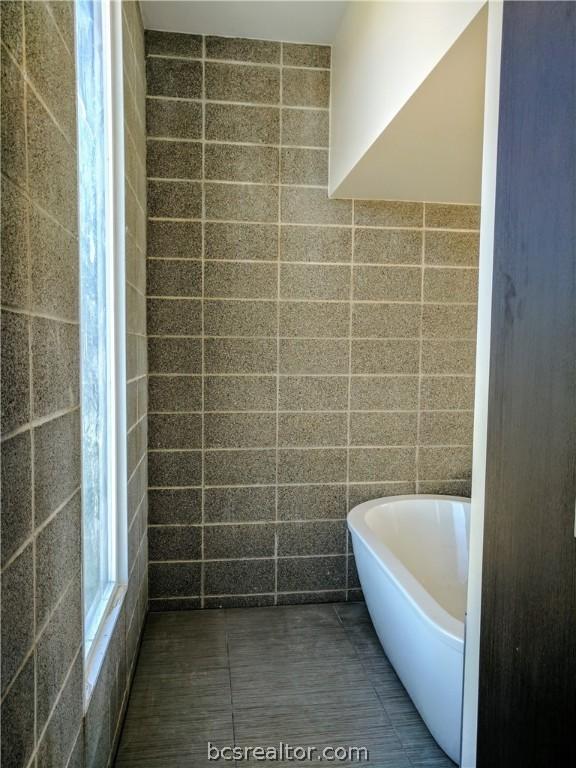 bathroom featuring a bathtub and tile walls