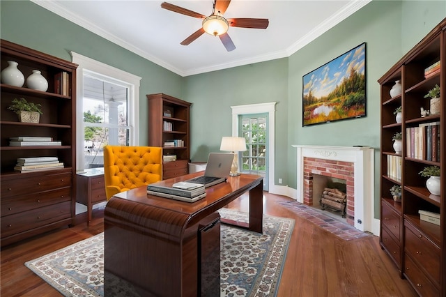 office area featuring crown molding, wood finished floors, a brick fireplace, and a ceiling fan