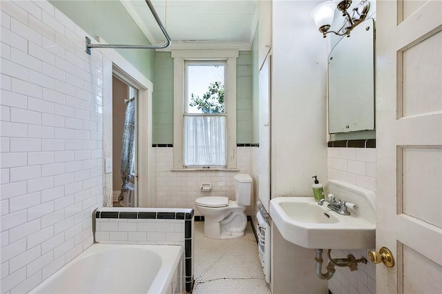 bathroom featuring a sink, toilet, tile walls, tile patterned flooring, and washtub / shower combination