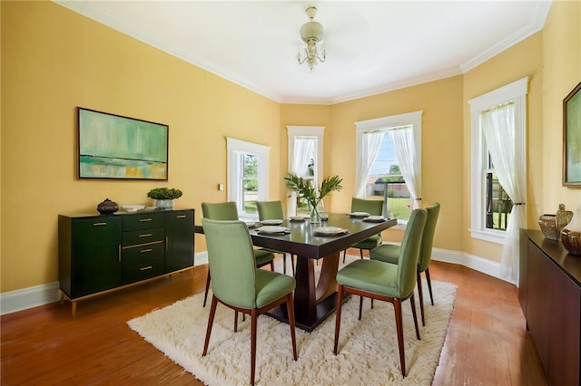 dining space featuring baseboards, wood finished floors, and ornamental molding