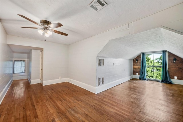 additional living space with wood-type flooring, baseboards, and visible vents