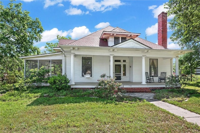 view of front of house with a chimney, a front yard, and covered porch