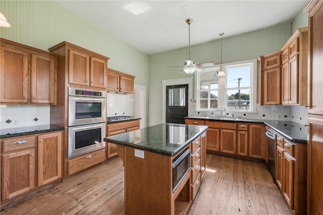 kitchen featuring wood-type flooring, brown cabinetry, appliances with stainless steel finishes, and decorative backsplash