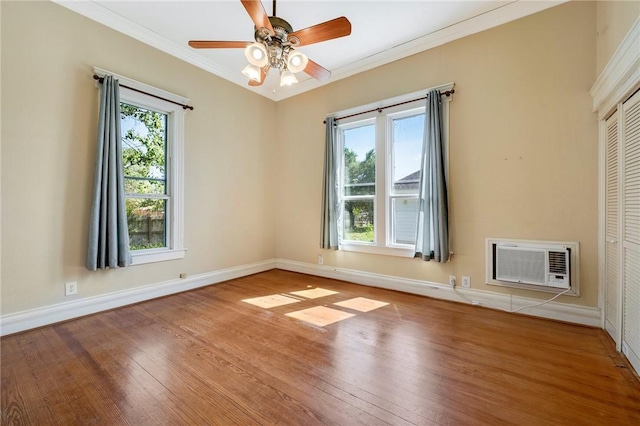 spare room with wood finished floors, a ceiling fan, crown molding, baseboards, and a wall mounted AC
