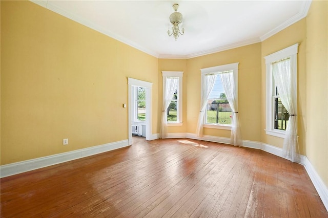 spare room featuring baseboards, a notable chandelier, ornamental molding, and wood-type flooring