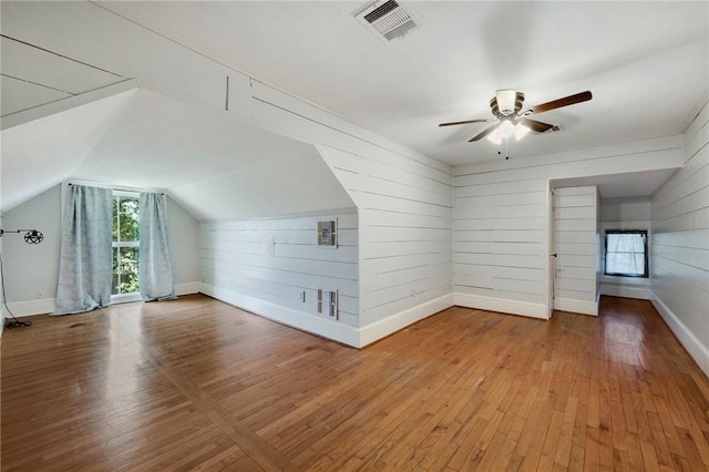 additional living space with vaulted ceiling, visible vents, baseboards, hardwood / wood-style flooring, and ceiling fan