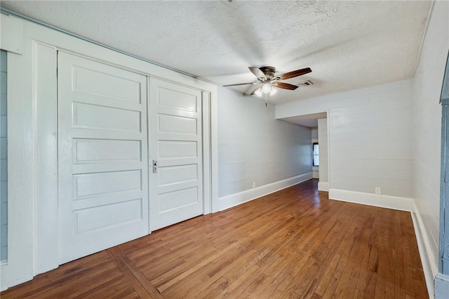 interior space with visible vents, baseboards, a textured ceiling, hardwood / wood-style flooring, and ceiling fan