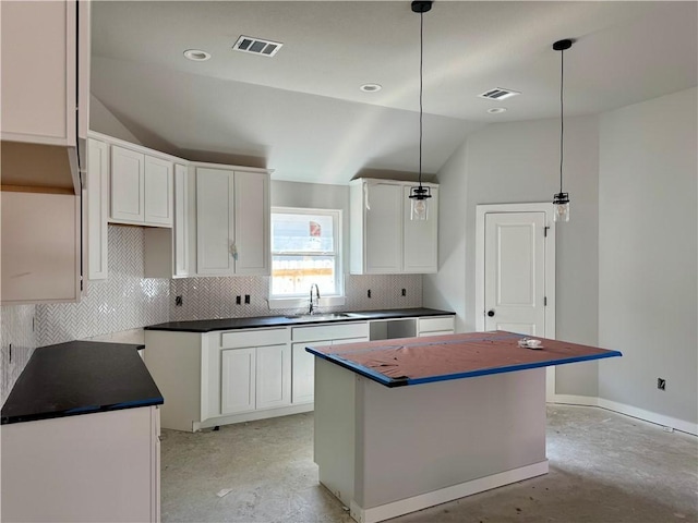 kitchen with lofted ceiling, sink, decorative light fixtures, a center island, and white cabinets