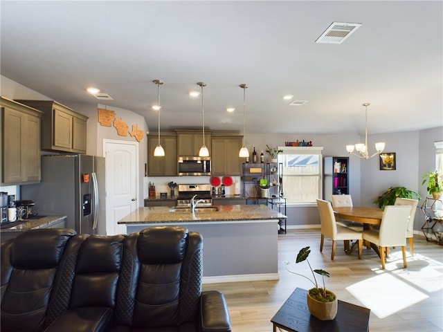 kitchen featuring an inviting chandelier, light hardwood / wood-style flooring, an island with sink, pendant lighting, and appliances with stainless steel finishes