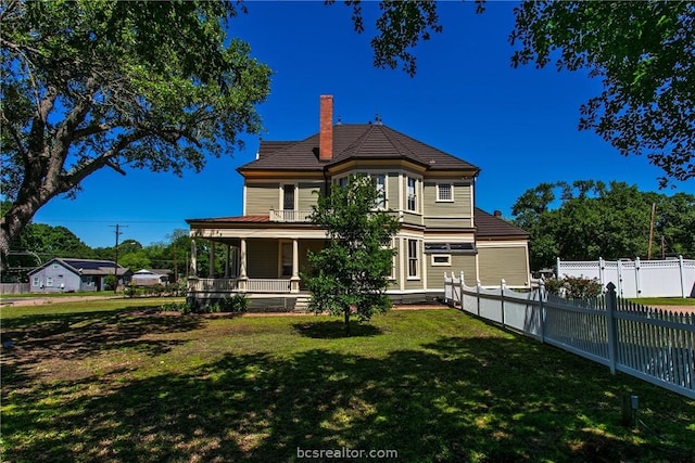 rear view of property featuring a porch and a yard