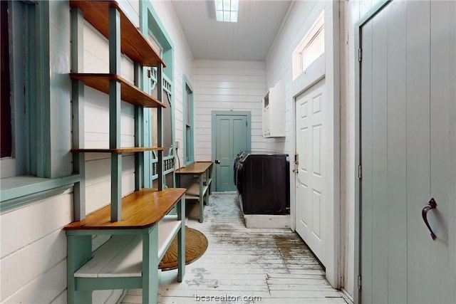 corridor with wood walls and light hardwood / wood-style flooring