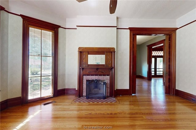 unfurnished living room featuring a fireplace, light hardwood / wood-style floors, and ceiling fan