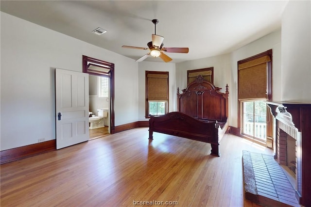 bedroom featuring ceiling fan, light hardwood / wood-style flooring, connected bathroom, and multiple windows