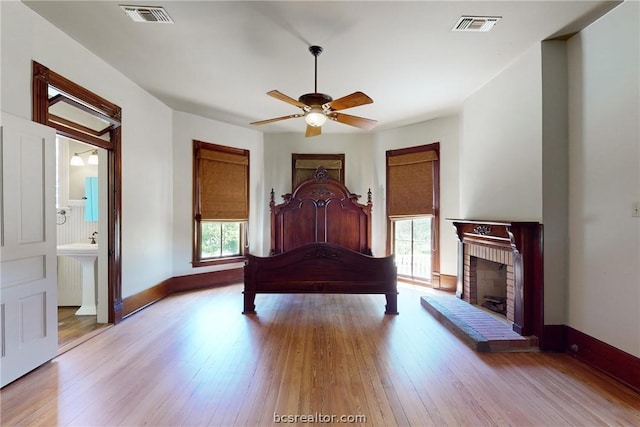 unfurnished bedroom featuring ensuite bathroom, multiple windows, and light hardwood / wood-style floors