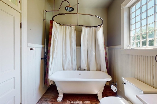 bathroom with a bathing tub, hardwood / wood-style floors, and toilet