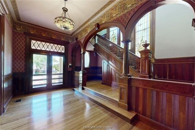 foyer with decorative columns, crown molding, light hardwood / wood-style flooring, and french doors