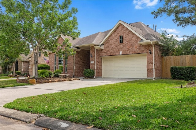 traditional home with a garage, fence, a front yard, brick siding, and driveway