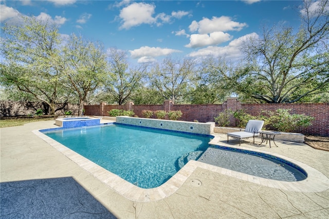 view of swimming pool featuring a fenced backyard, a pool with connected hot tub, and a patio