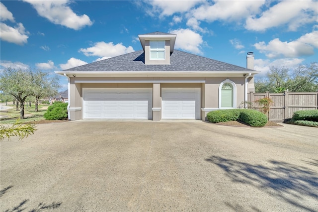 exterior space with stucco siding, a chimney, fence, and concrete driveway