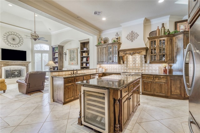 kitchen featuring visible vents, a peninsula, a sink, custom range hood, and beverage cooler