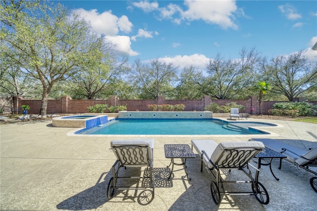 view of pool featuring a fenced backyard, a pool with connected hot tub, and a patio area