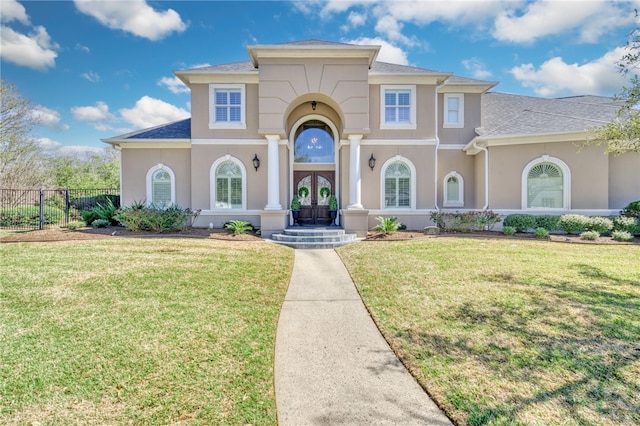 mediterranean / spanish house featuring french doors, roof with shingles, stucco siding, fence, and a front lawn
