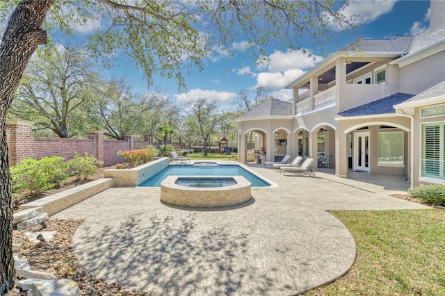 view of pool with french doors, a pool with connected hot tub, fence, and a patio
