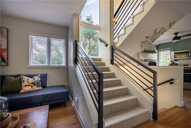 stairway with hardwood / wood-style floors, plenty of natural light, and ceiling fan