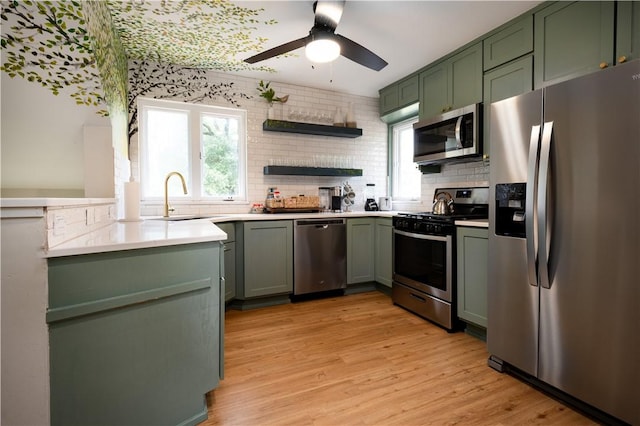 kitchen featuring decorative backsplash, stainless steel appliances, sink, light hardwood / wood-style floors, and green cabinets