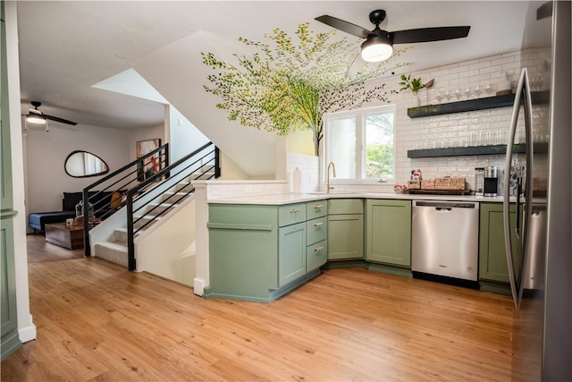 kitchen with ceiling fan, sink, green cabinetry, appliances with stainless steel finishes, and light wood-type flooring