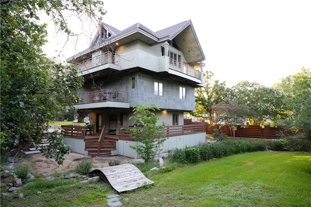 rear view of house with a yard and a balcony