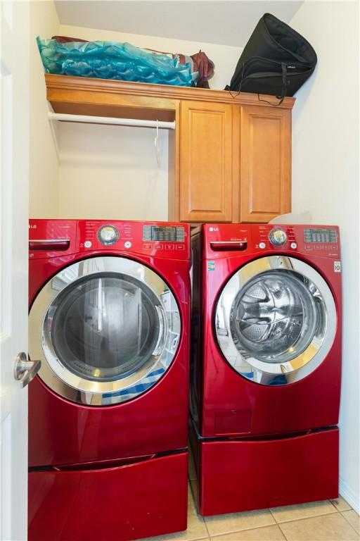 305 Holleman Dr E Unit 202, College Station, TX 77840 - laundry area with washing machine and clothes dryer, cabinet space, and light tile patterned floors