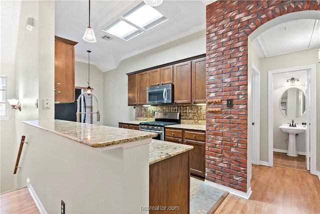 kitchen featuring light stone counters, kitchen peninsula, light hardwood / wood-style floors, decorative light fixtures, and appliances with stainless steel finishes